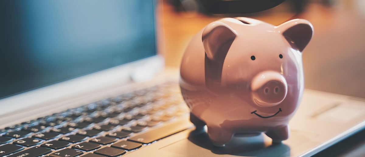 A pink piggy bank on a laptop.