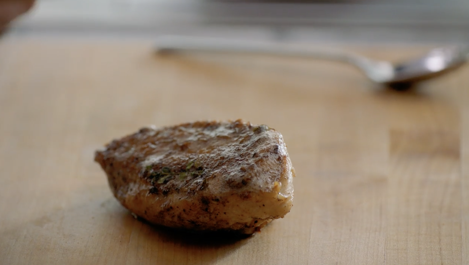 Cooked chicken breast on wood cutting board