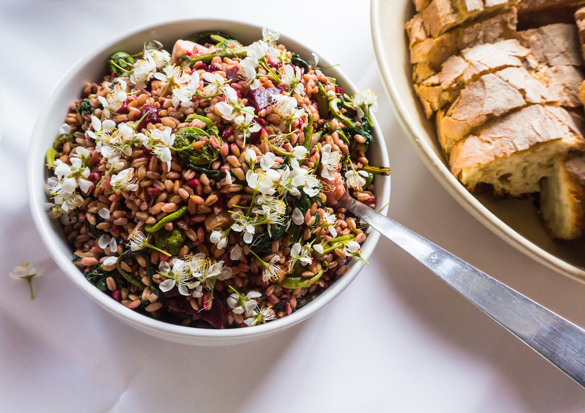 Farro salad in bowl with utensil and bread