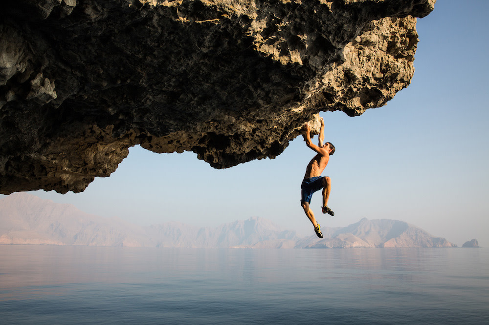 Jimmy Chin's photograph of a man rockclimbing over water in natural light