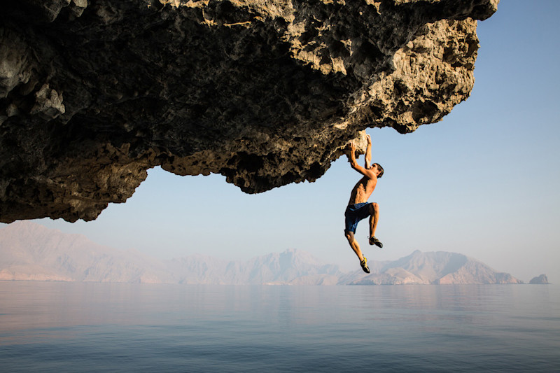 Jimmy Chin's photograph of a man rockclimbing over water in natural light