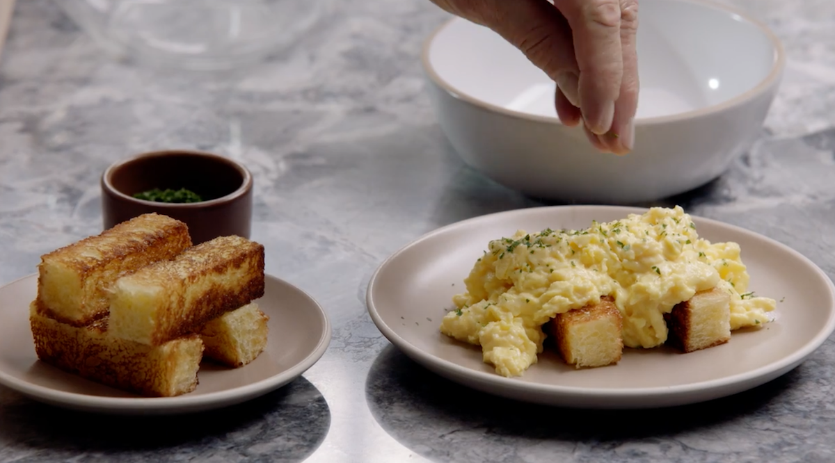 Scrambled eggs being garnished with side of bread