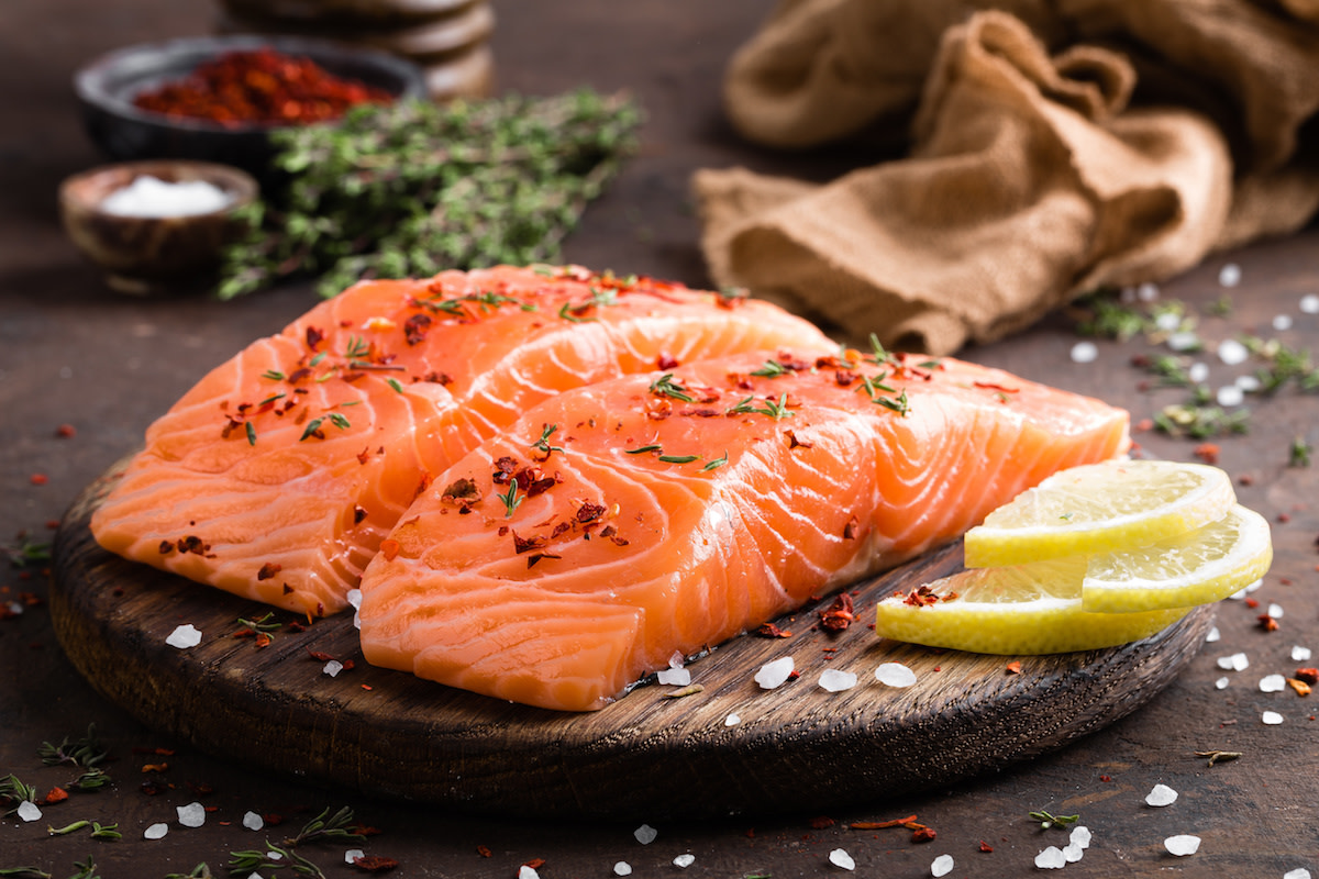 Raw salmon filets on wood plank with lemon