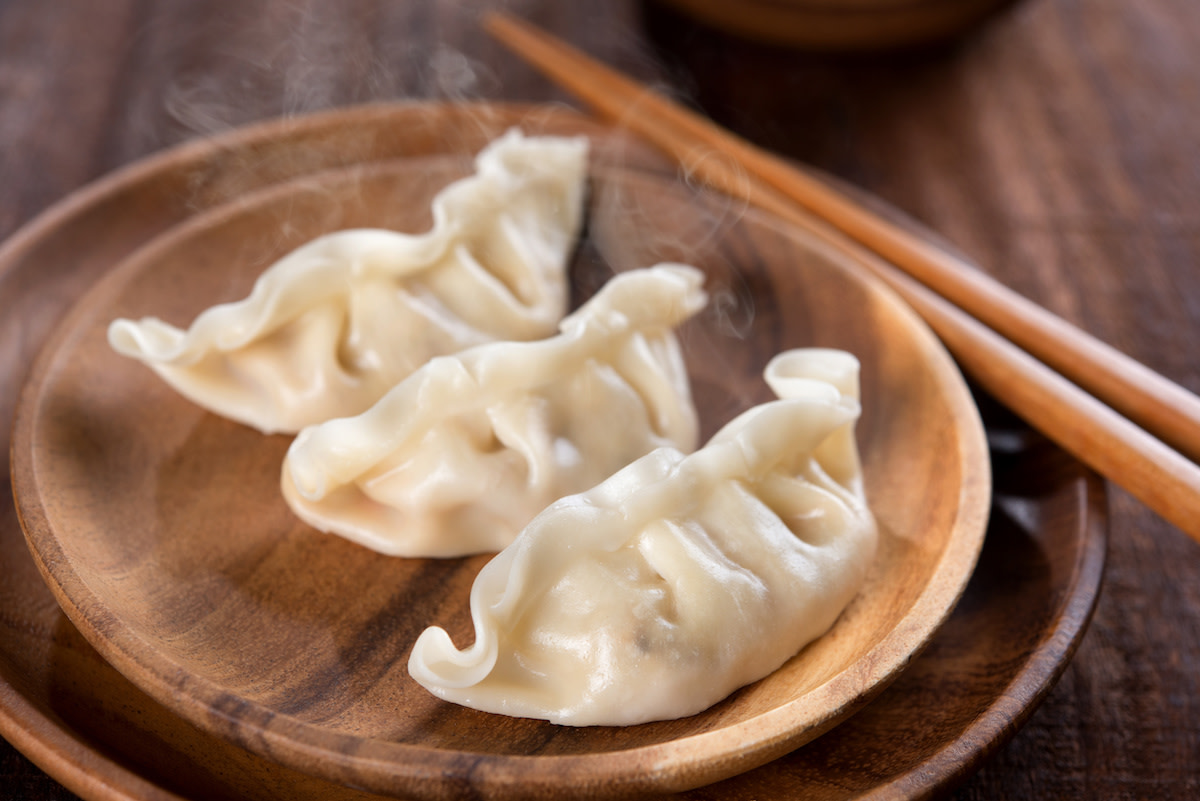 Asian dumplings on wood plate with chopsticks