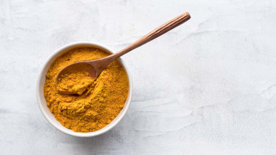 Turmeric powder in bowl with wooden spoon