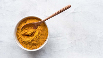 Turmeric powder in bowl with wooden spoon
