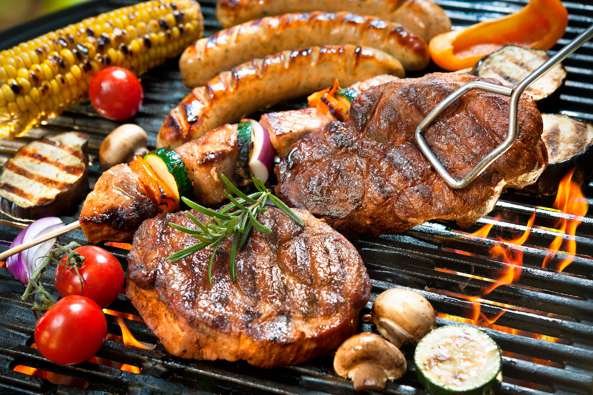 Meats and vegetables being grilled with flame