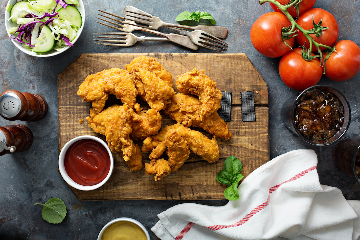 Fried chicken with condiments on wood board with forks