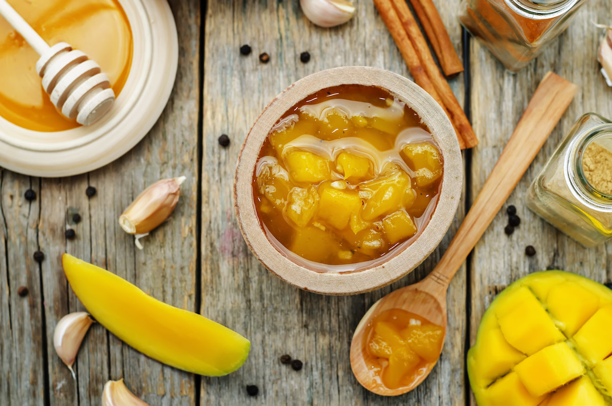 Chutney in bowl with mangos and honey on wood