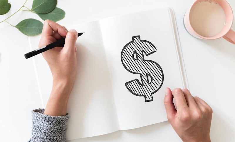 A person drawing a dollar sign, representing macroeconomics ad the study of economic output