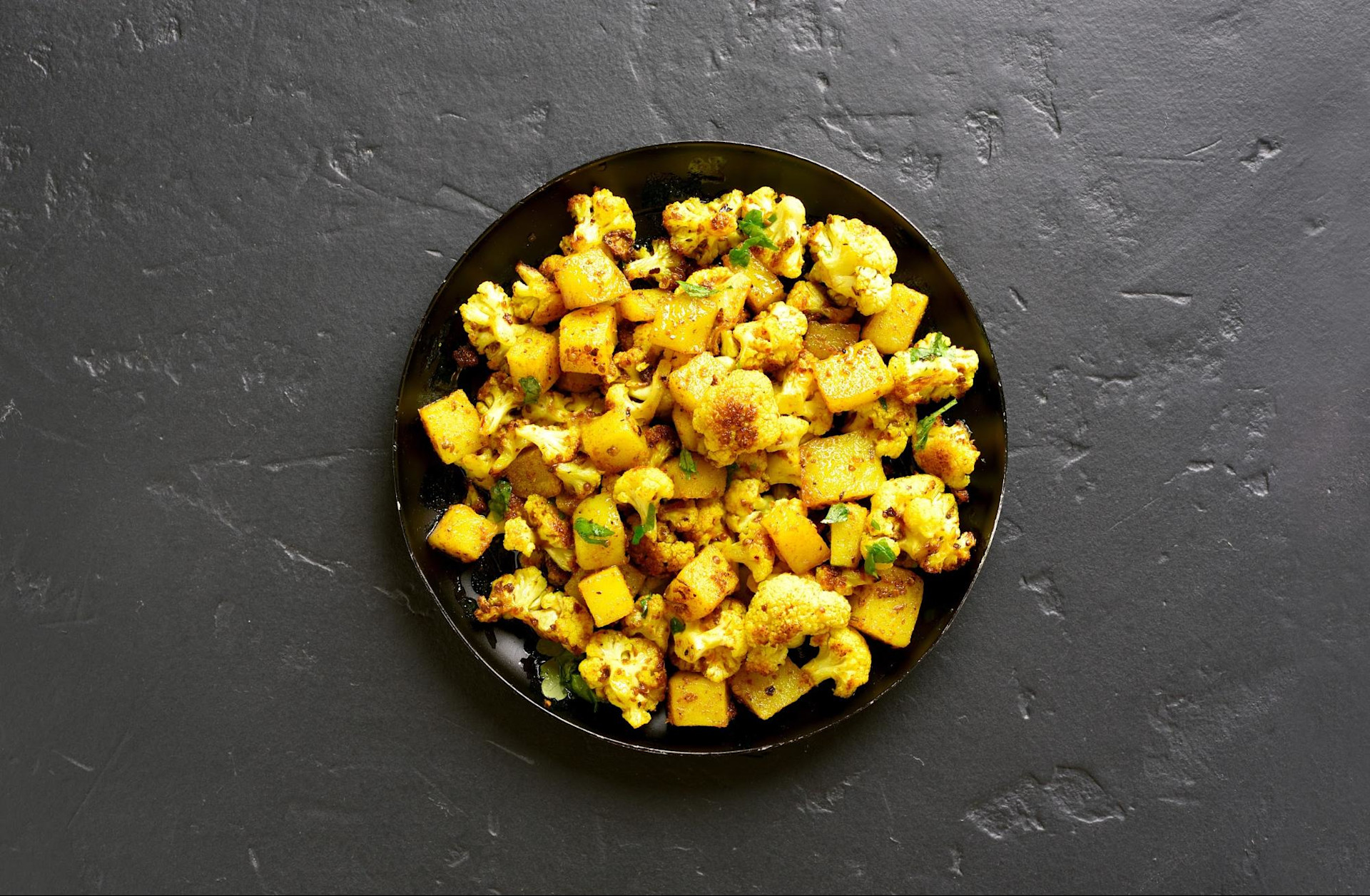 Aloo gobi cauliflower in bowl on gray background