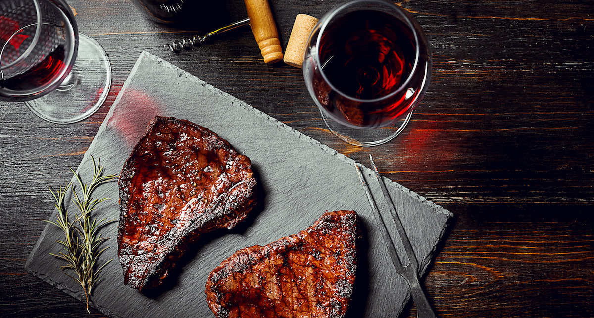 Steaks with red wine on slab with rosemary