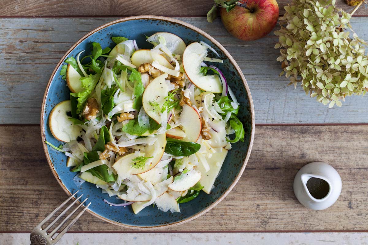 Fennel and apple salad with greens on rustic wood