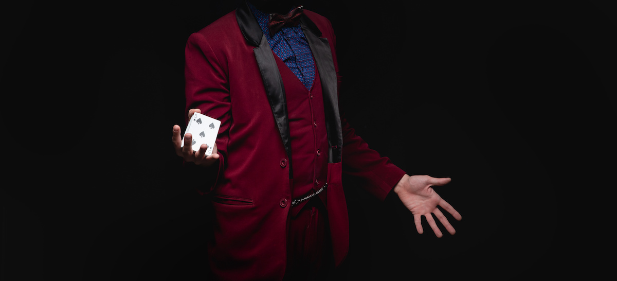 Мужчина с карточкой в руке на темном фоне. Загадочный мужчина держит игральные кости.
