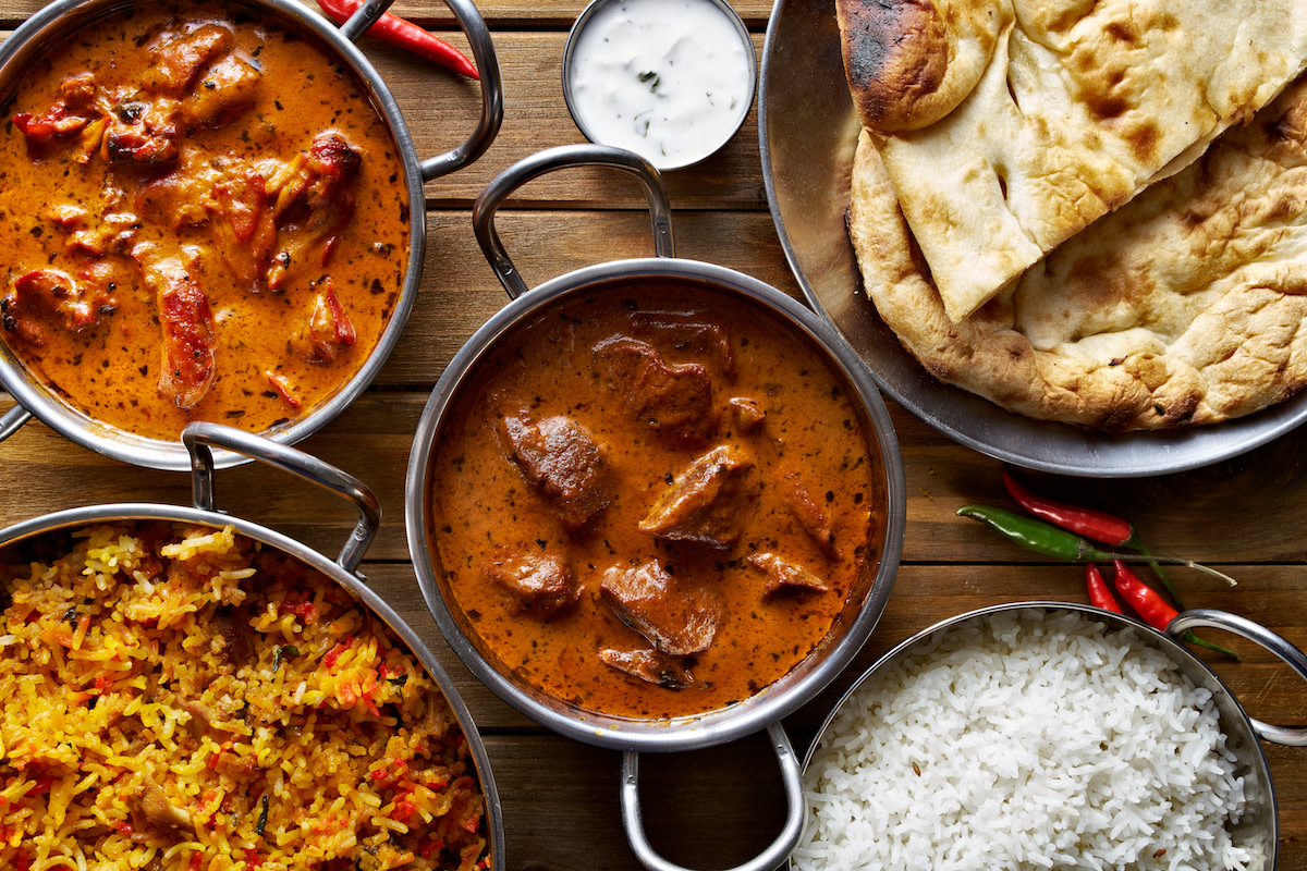 Indian dishes in bowls with naan and rice