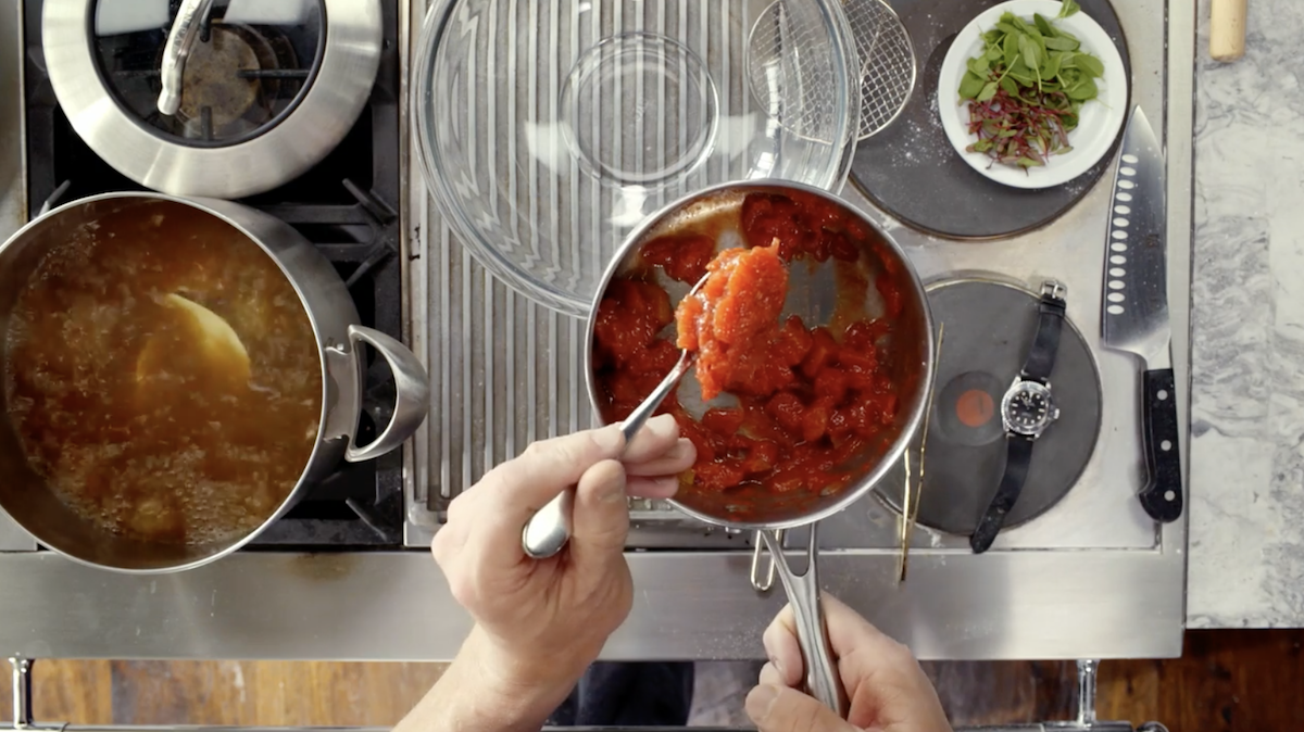 Tomato chutney in spoon above pot