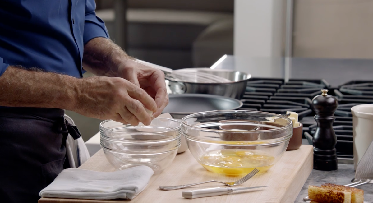 Thomas Keller cracking eggs in glass bowl