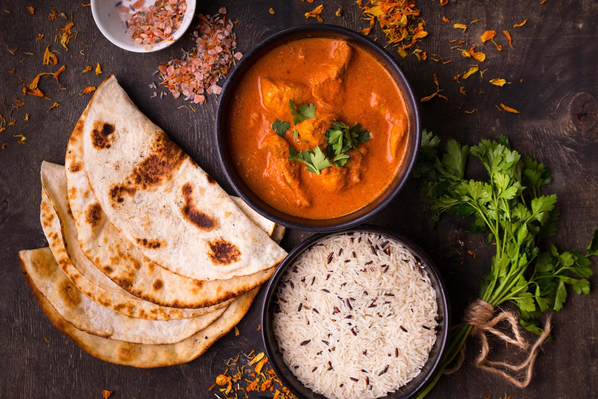 Chicken tikka masala in bowl with naan and rice