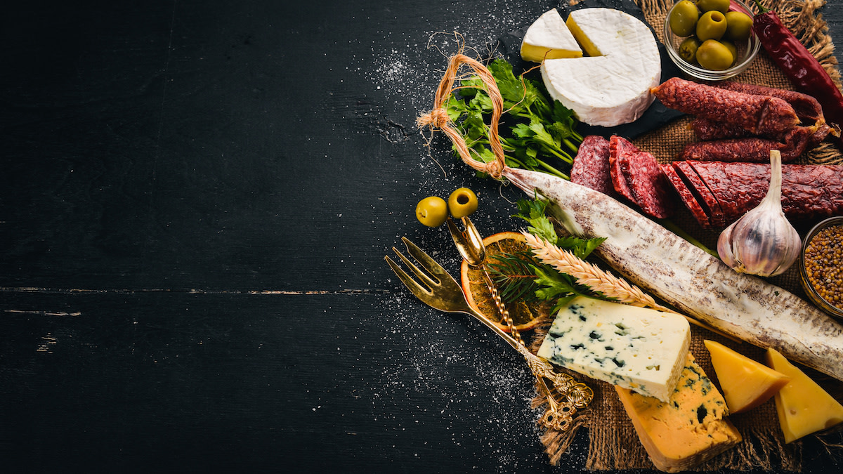 Meats, cheeses, and bread on black background