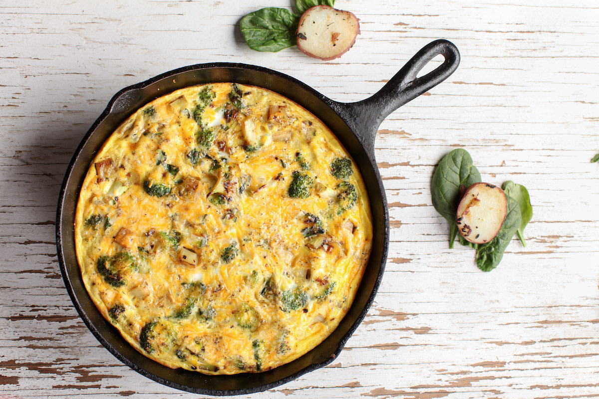 Egg frittata in cast iron skillet on white wood