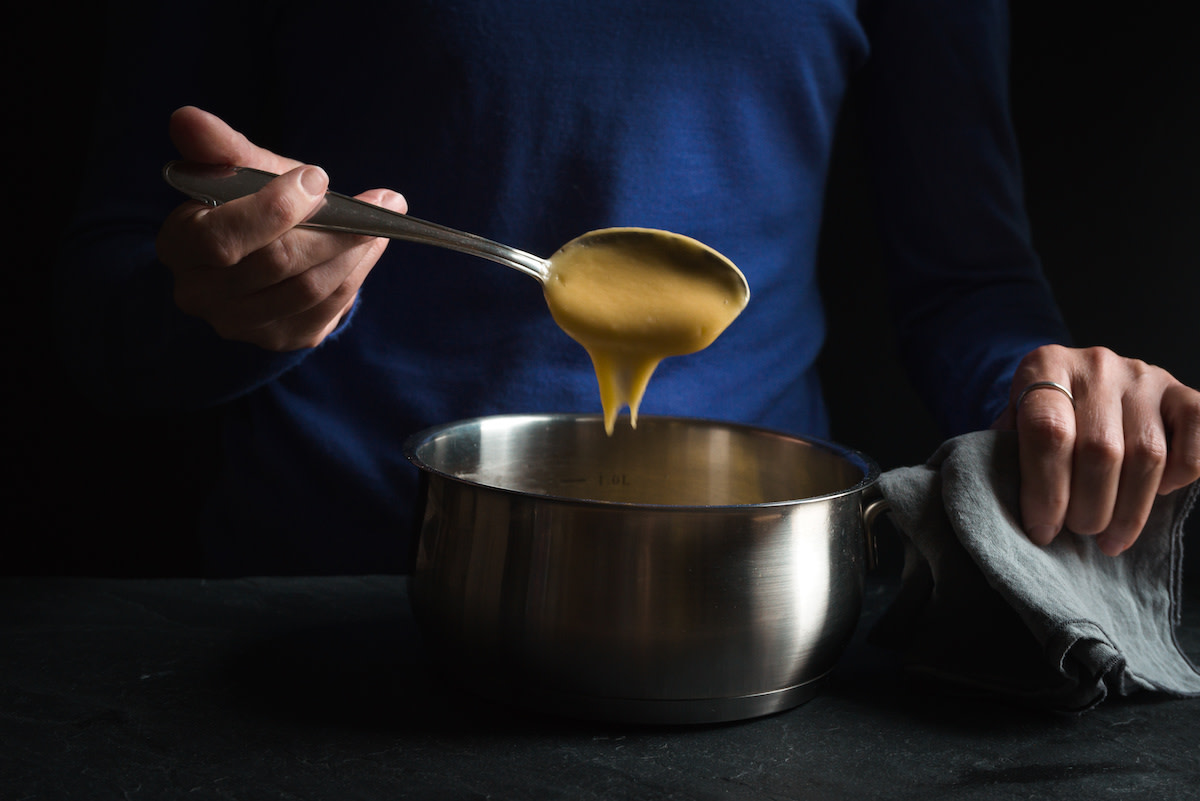 Person scooping roux with spoon out of bowl