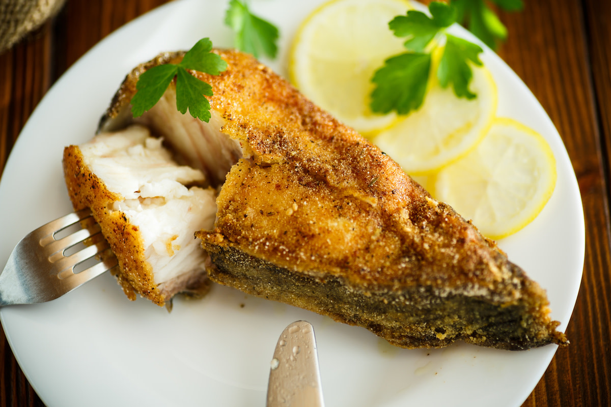 Fried catfish on plate with lemon and herbs