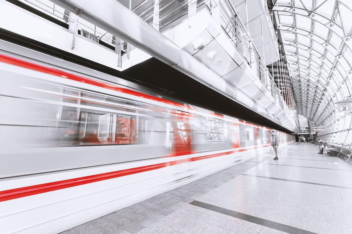 Blurry red and white subway train with person waiting