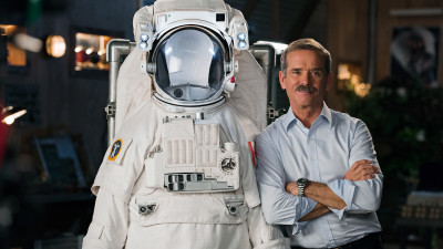 Chris Hadfield standing next to a astronaut suit