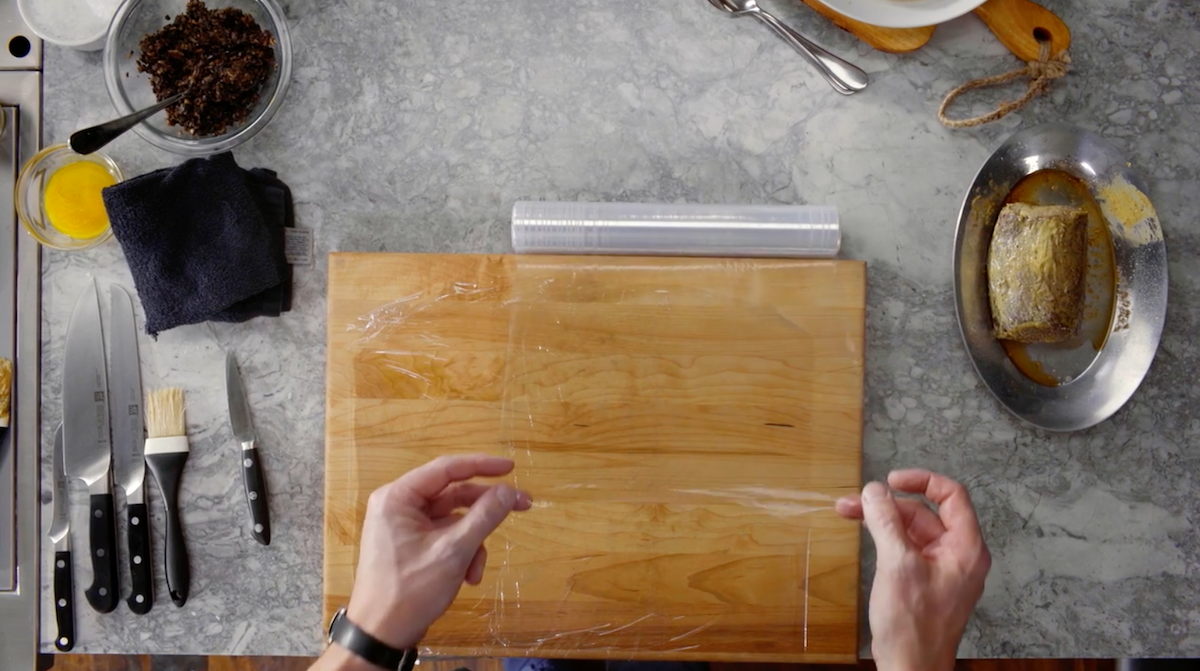 Gordon Ramsay pulling plastic wrap over cutting board