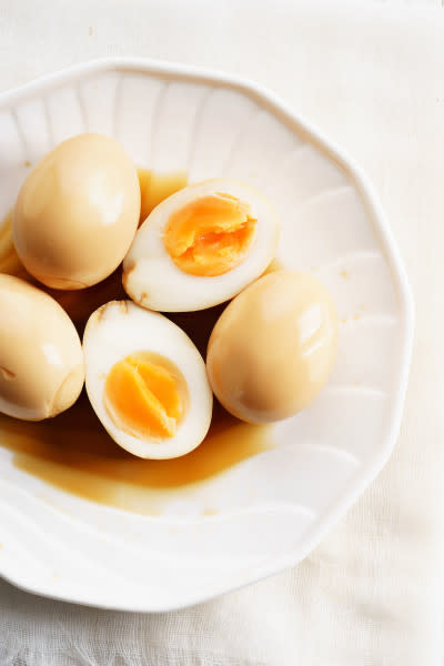 Soft boiled eggs in soy sauce in white bowl