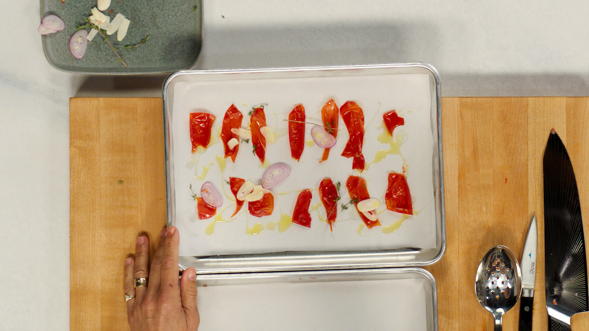 Seasoning tomato skins with garlic, shallots, thyme, olive oil, and kosher salt.