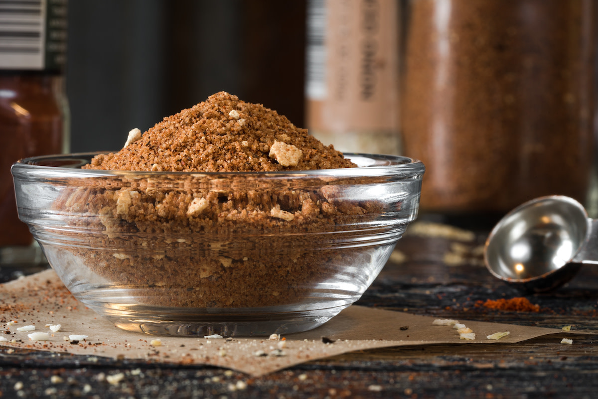 Dry rub in glass bowl with seasoning in background