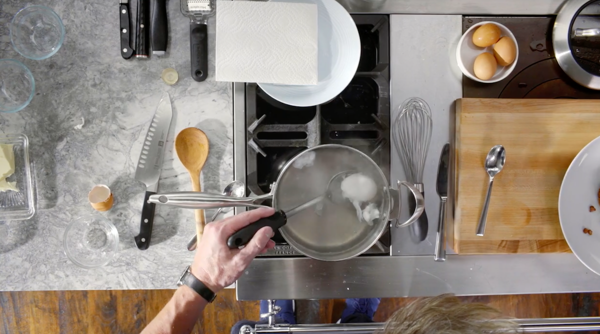 Gordon Ramsay lifting poached egg out of water with spoon