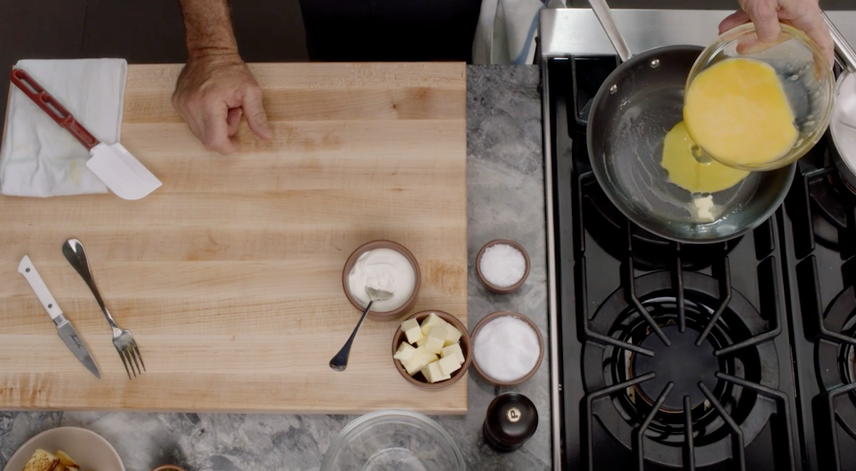 Thomas Keller pouring scrambled eggs into pan