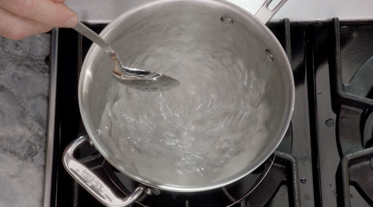 Boiling water being swirled around in pot with spoon