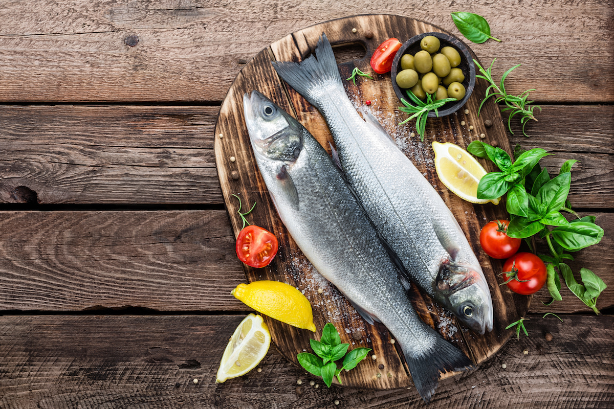 Raw bass with tomatoes and lemon on wood