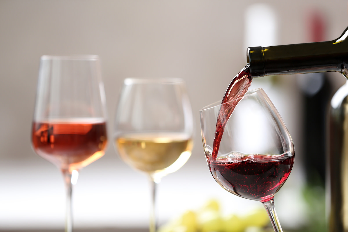 Red wine being poured into glass with other wines in background