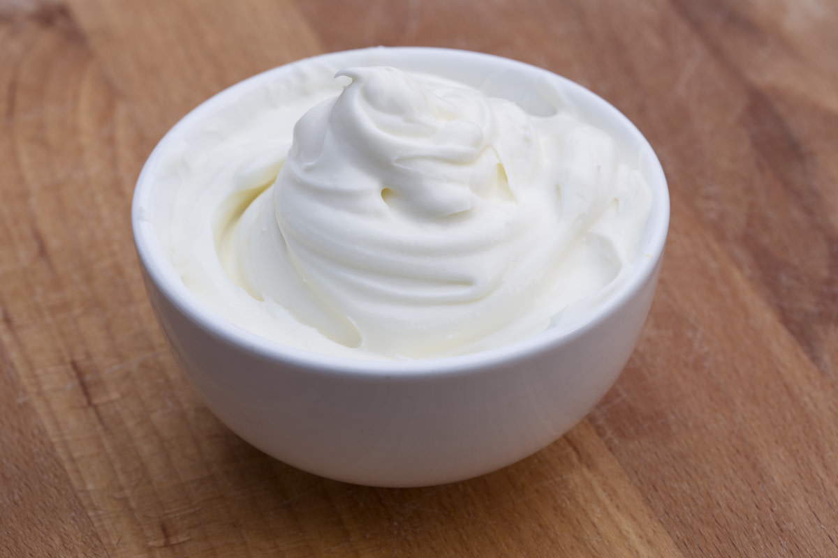 Sour cream in bowl on wood table