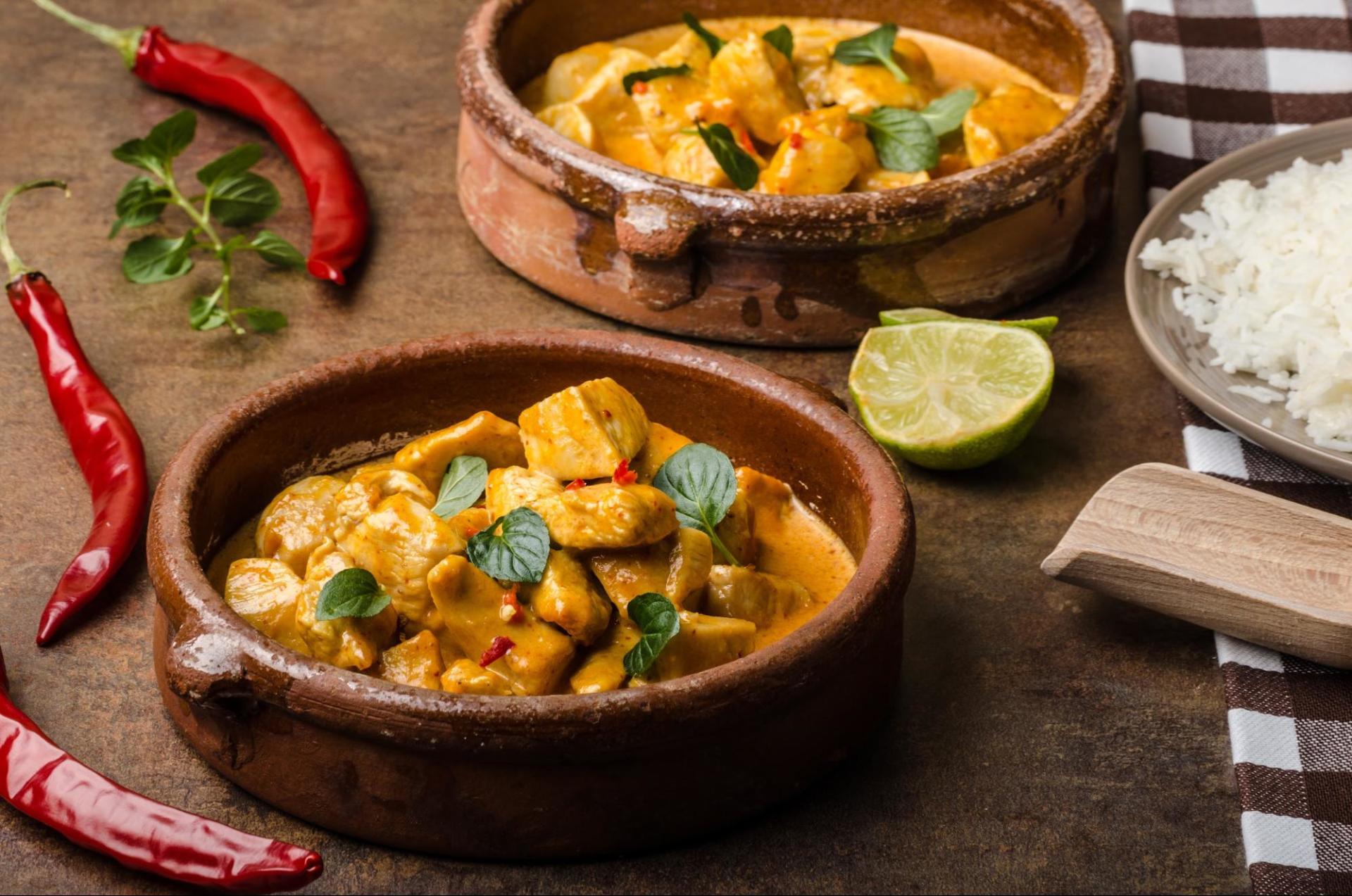 indian butter chicken in bowl with rice and limes