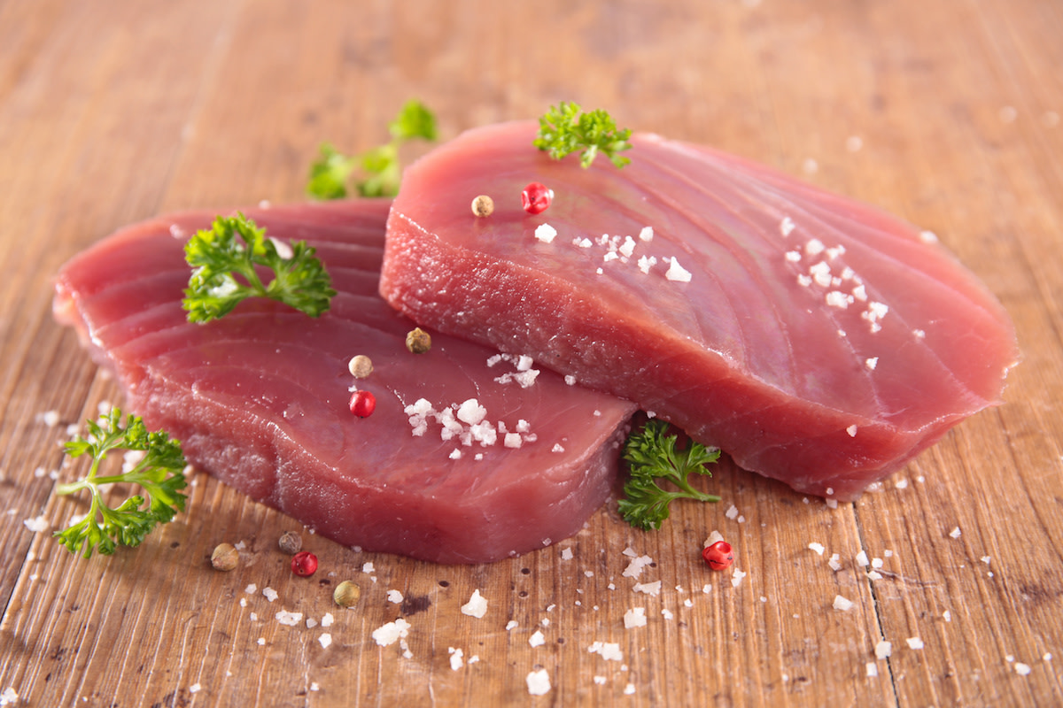 Raw tuna filets with salt and pepper and herbs on wood