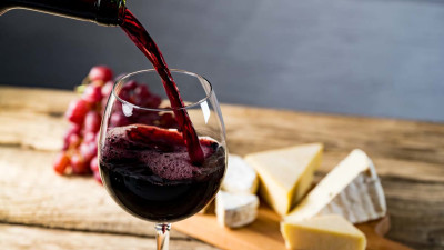 Pouring red wine into glass with cheese