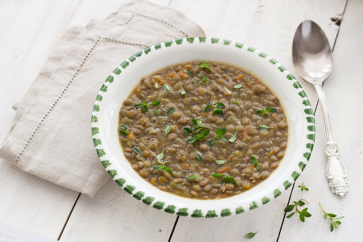 Lentil soup with spoon and napkin on white wood