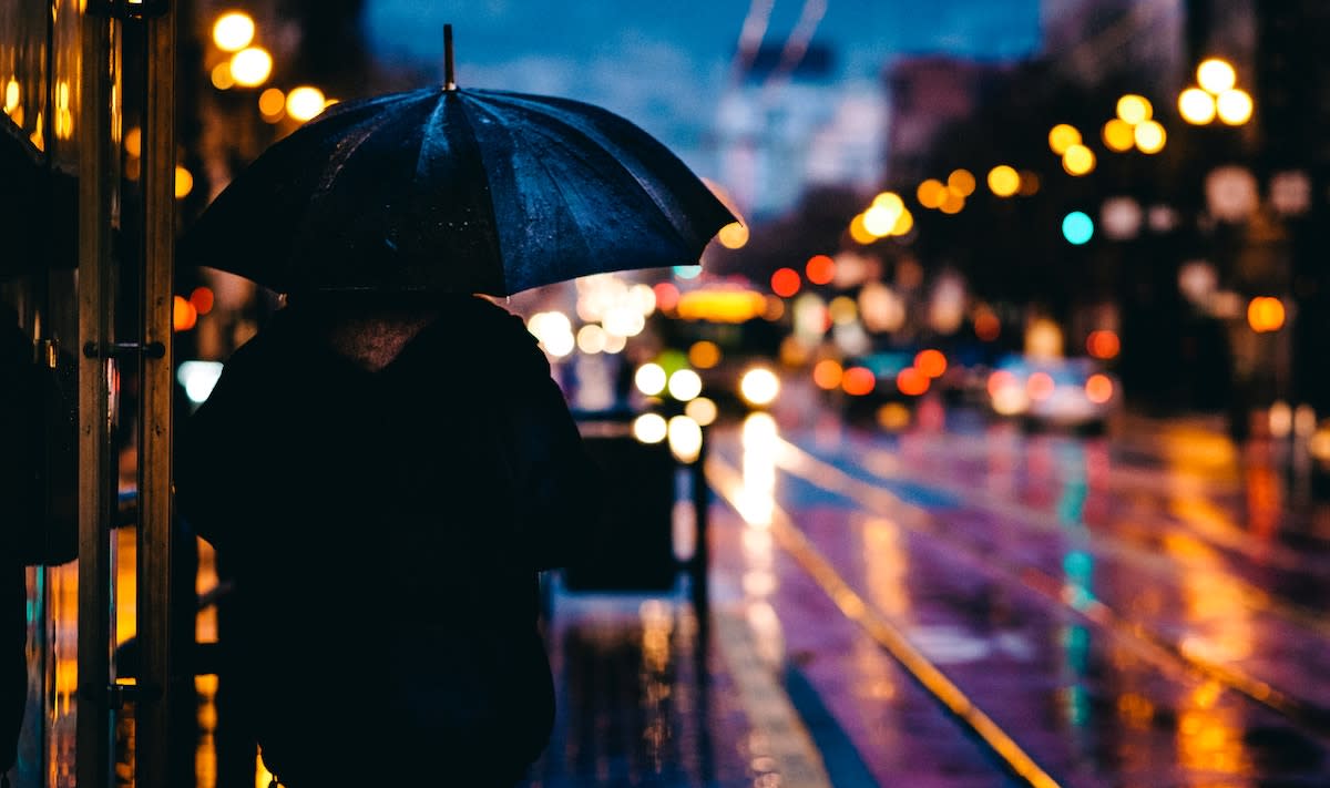 Person under an umbrella with blurred city lights in background