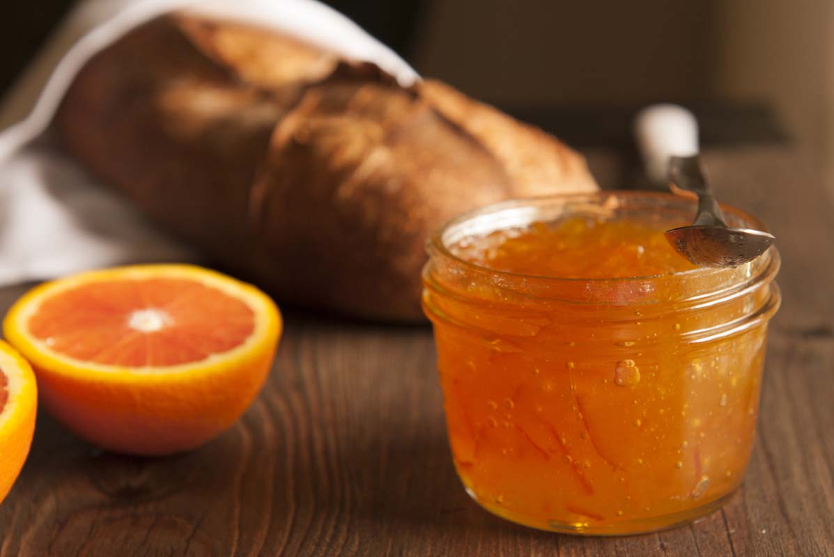 Jar of orange marmalade with rustic bread