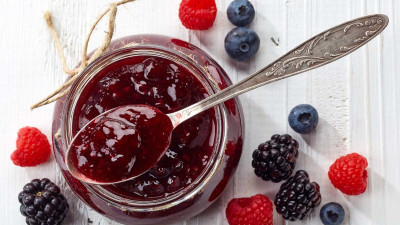 Jam in jar with spoon and berries