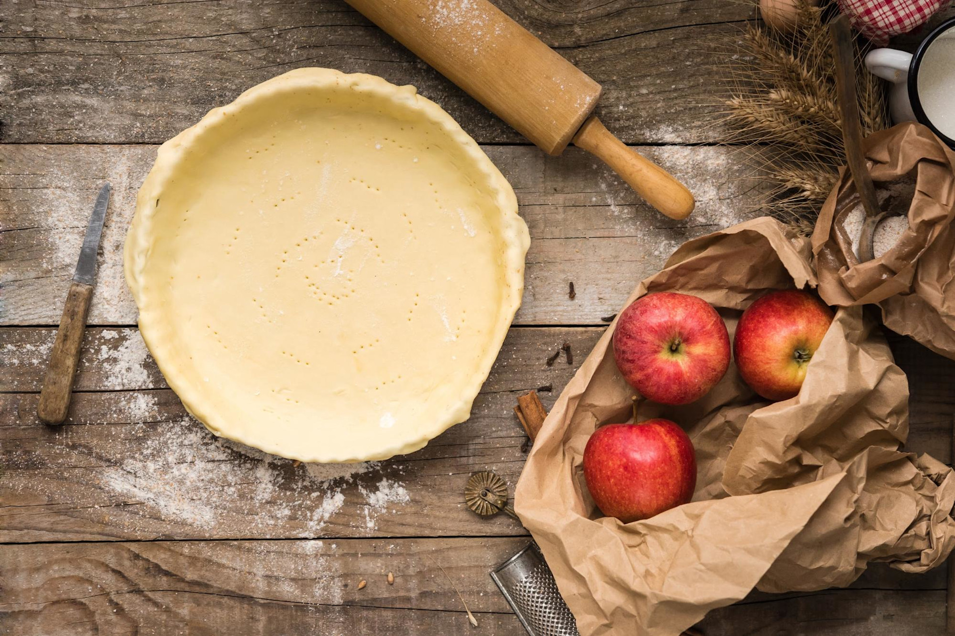 Pie crust in pie pan with apples and rolling pin