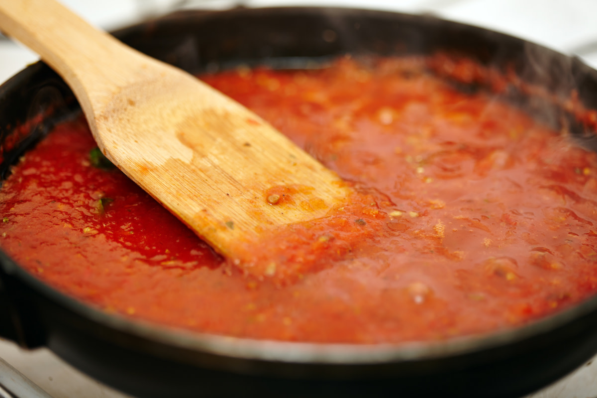 Pasta sauce simmering in pan with wooden spoon