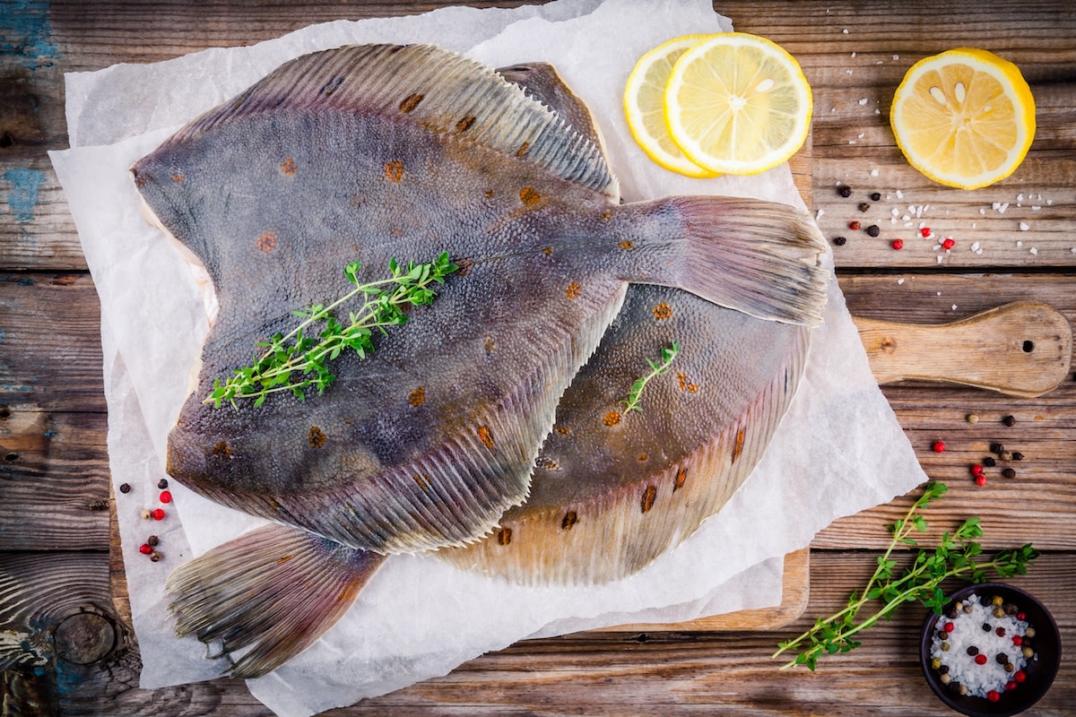 Raw Flounder on parchment paper with herbs and lemon