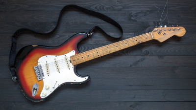 Electric guitar with strap on dark gray wood