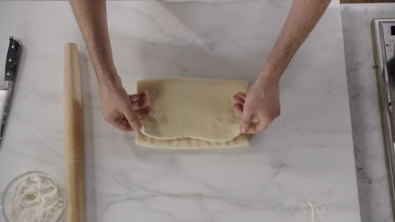 Dominique Ansel folding dough on marble counter